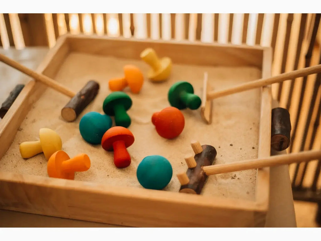 Wooden tray containing colorful wooden mushroom-shaped toys and mallets.