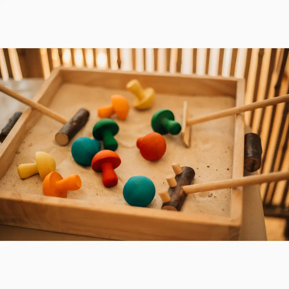 Wooden tray containing colorful wooden mushroom-shaped toys and mallets.