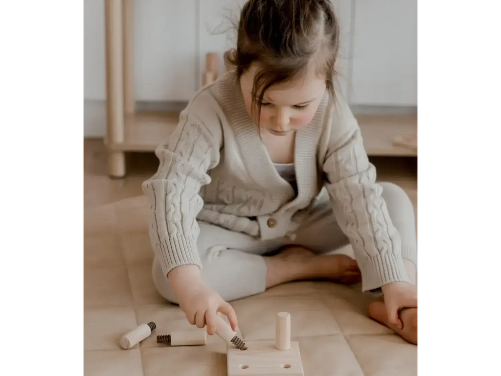 Child playing with wooden toy tools.