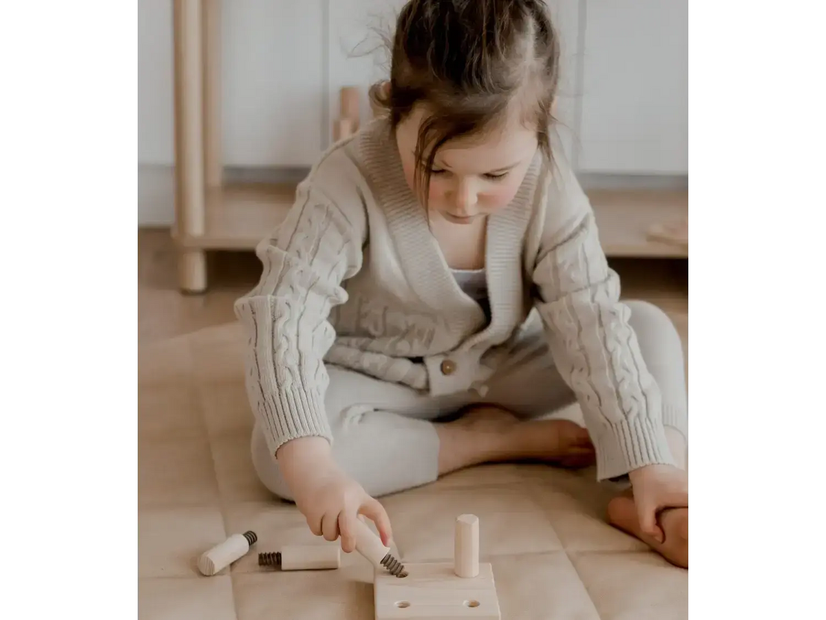 Child playing with wooden toy tools.