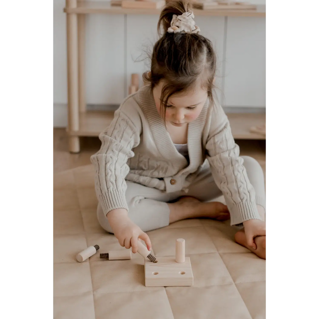 Child playing with wooden toy tools.