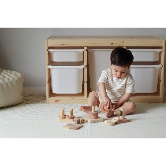 Child sitting on a carpet playing with wooden toys.