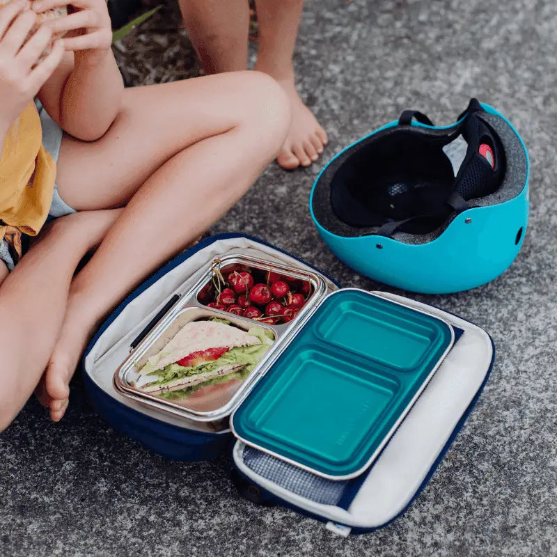 Lunchbox containing a sandwich and cherries, with a separate turquoise container nearby.