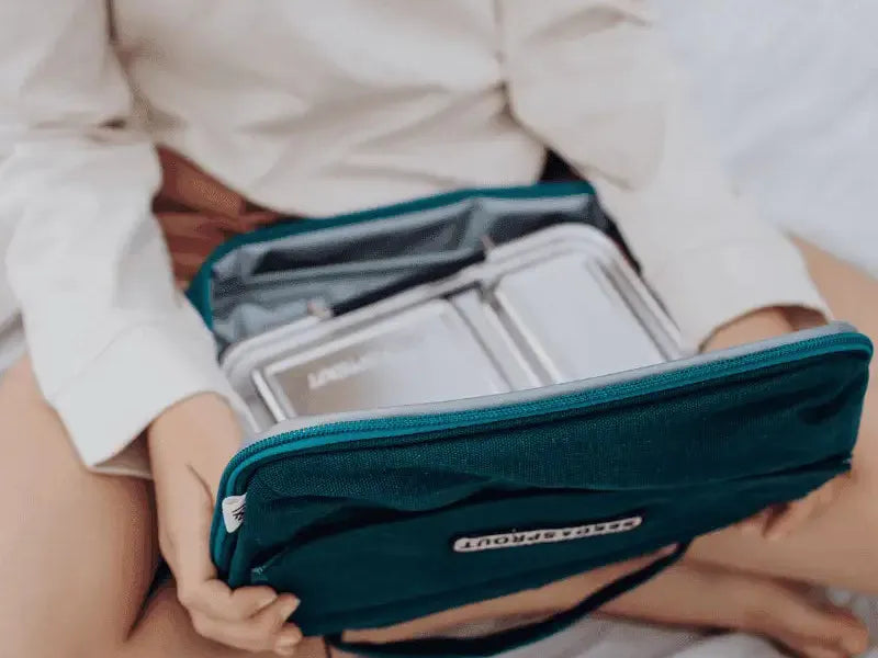 Teal travel organizer or toiletry bag with multiple compartments being held open.