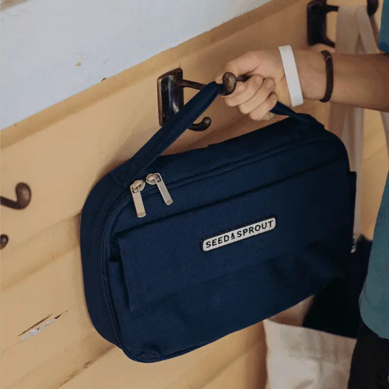 Navy blue ’Feed Leproud’ branded fanny pack or waist bag being hung on a hook.