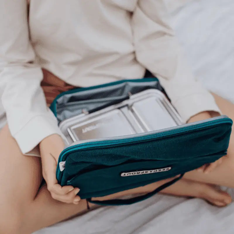 Teal travel organizer or toiletry bag with multiple compartments being held open.