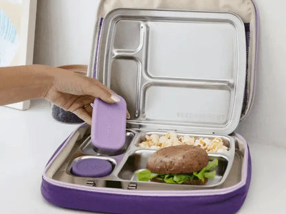Compartmentalized lunchbox with purple exterior and stainless steel interior sections containing various food items.