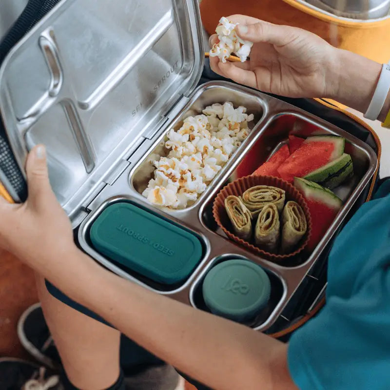 Stainless steel lunchbox with compartments containing various foods.