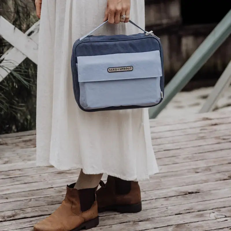 Two-toned blue rectangular bag with a handle and front pocket.