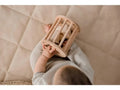 Wooden cylindrical cage or rattle held by small hands.