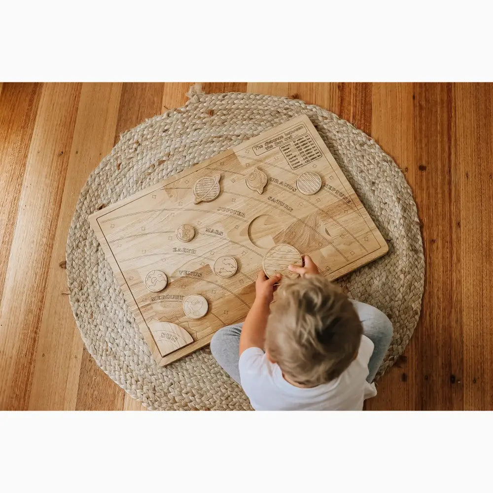 Wooden puzzle board with various shaped pieces being manipulated by a child’s hands.