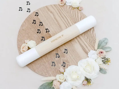 Wooden circular board decorated with flowers and musical notes, featuring a white rolling pin.