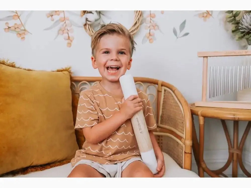 Smiling young child holding a rolled-up paper or poster.