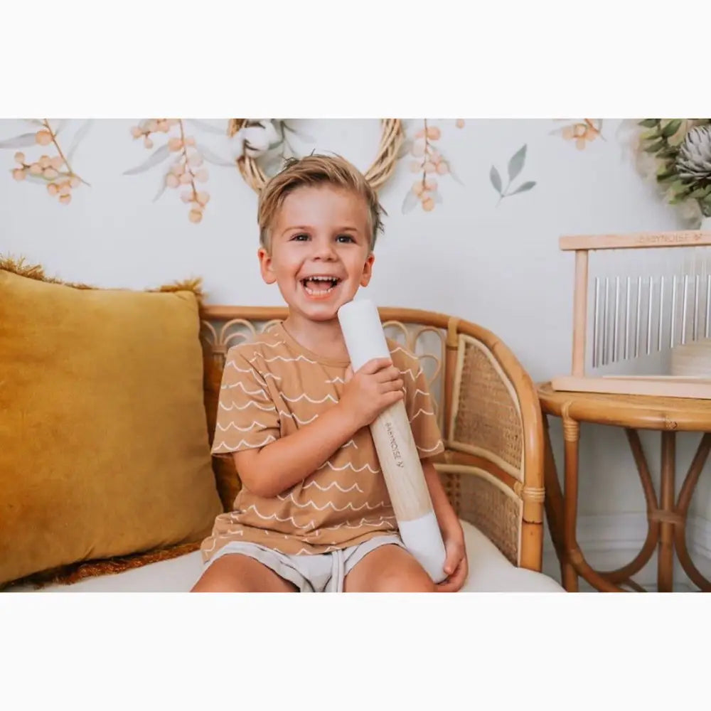 Smiling young child holding a rolled-up paper or poster.