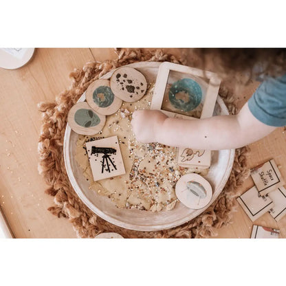 Circular white tray containing various small objects and a person’s hand.