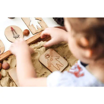 Child’s hands working with clay or dough, pressing a wooden mold into it.