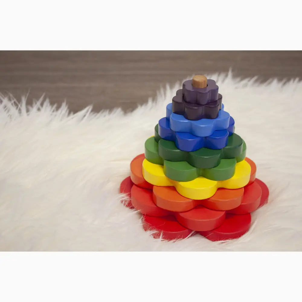 Colorful wooden stacking toy in the shape of a flower with rainbow-hued petals.