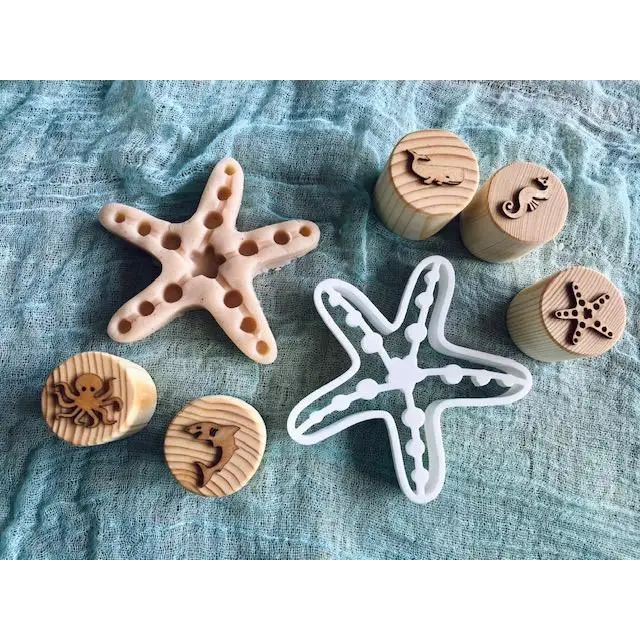 Wooden and ceramic starfish-shaped objects alongside round wooden stamps with marine creature designs.