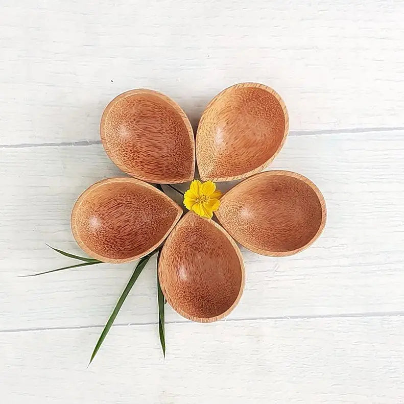 Flower-shaped arrangement of wooden spoons with a yellow center and green leaf accents.