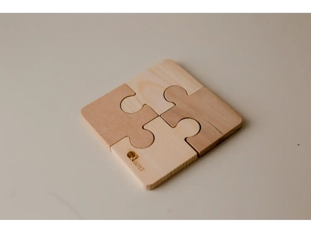 Four-piece wooden puzzle coaster with interlocking jigsaw shapes.