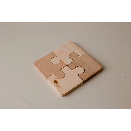 Four-piece wooden puzzle coaster with interlocking jigsaw shapes.