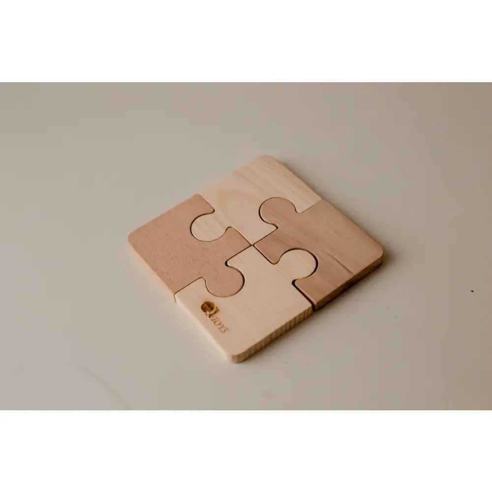 Four-piece wooden puzzle coaster with interlocking jigsaw shapes.