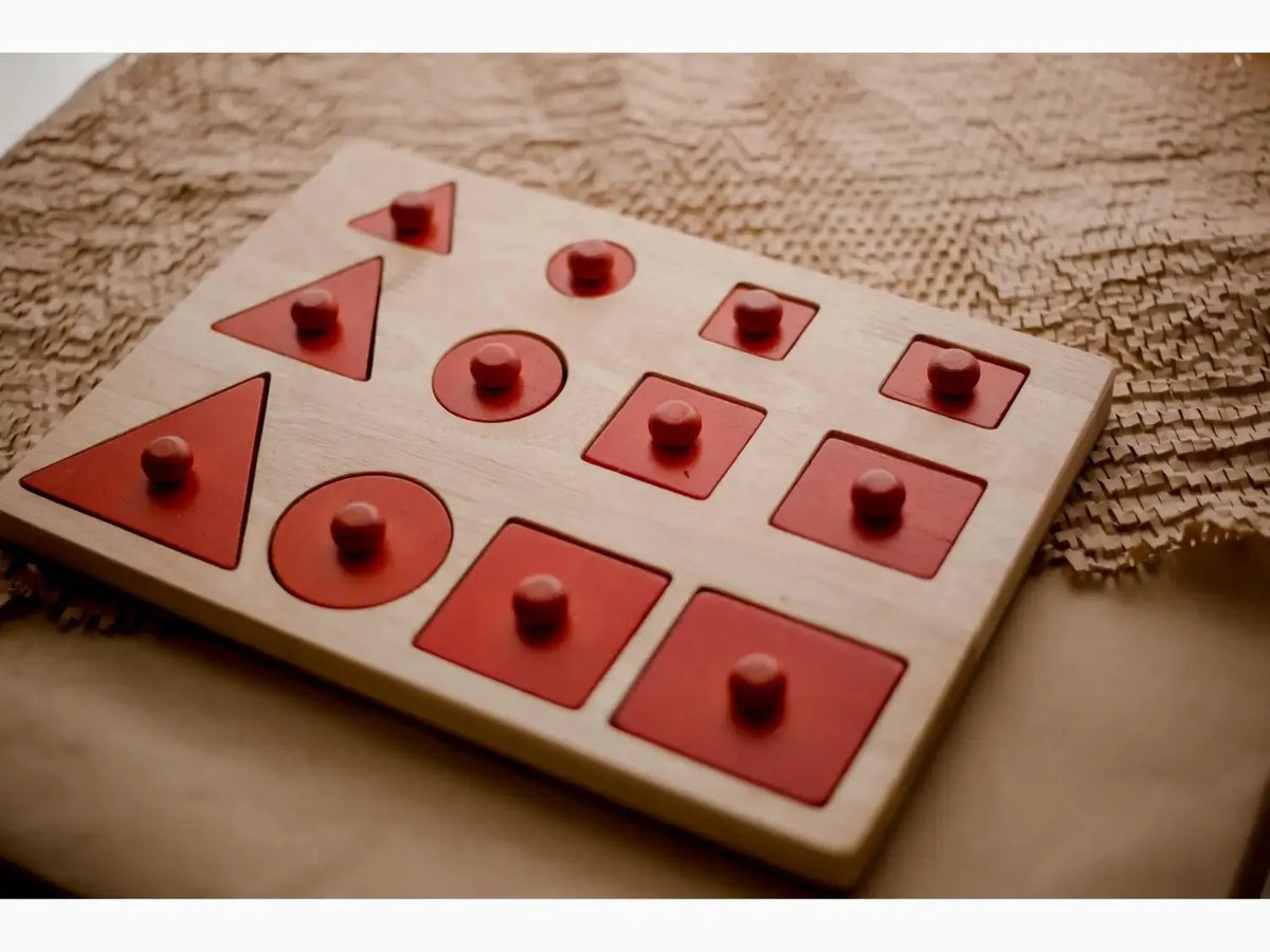 Wooden shape sorter toy with red geometric cutouts and matching pegs.