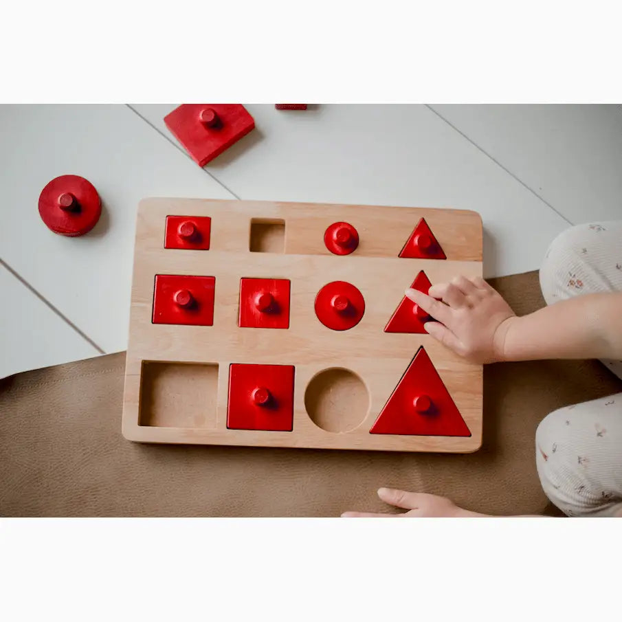 Wooden shape sorting toy with red pieces.