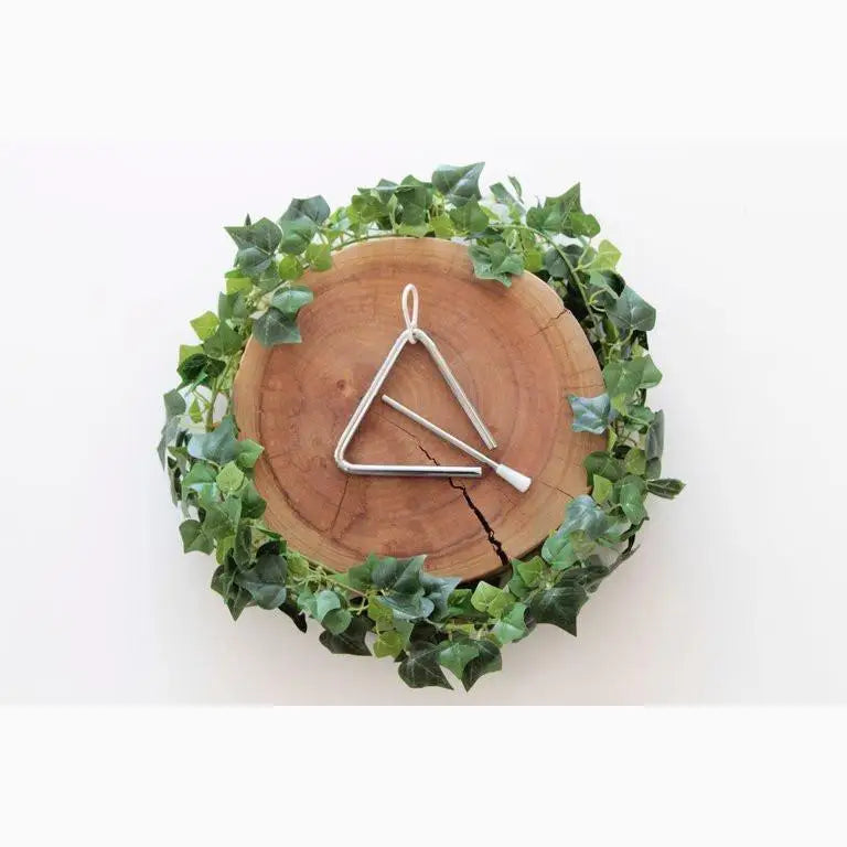 Triangle-shaped musical instrument on a wooden disc surrounded by green ivy leaves.