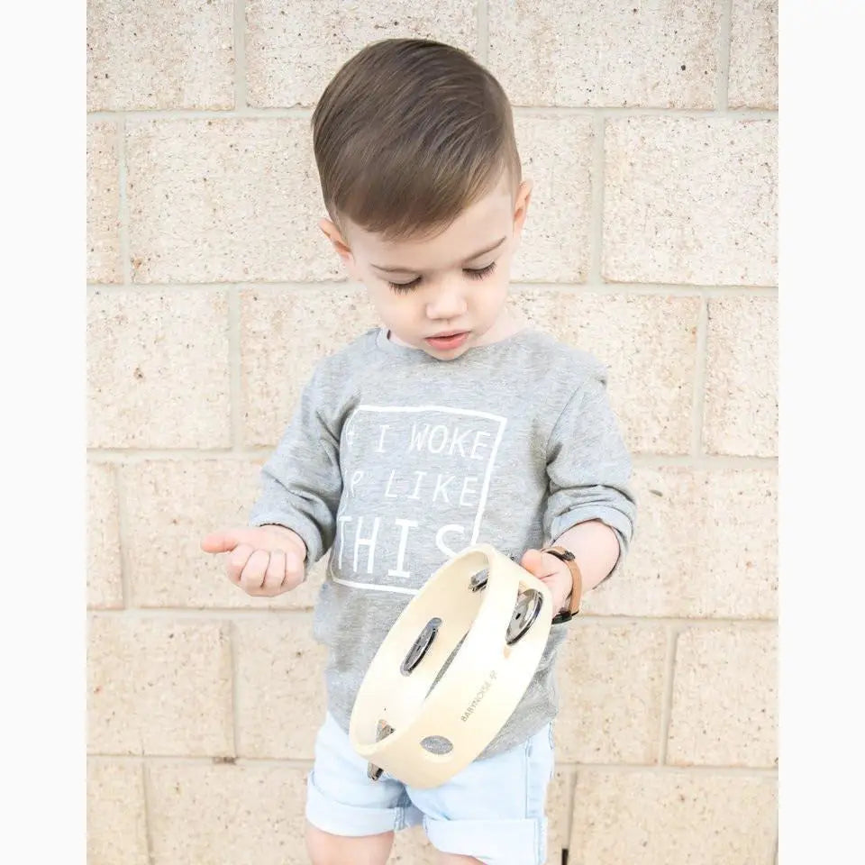 Young child wearing a gray sweatshirt and light blue shorts holding a toy.