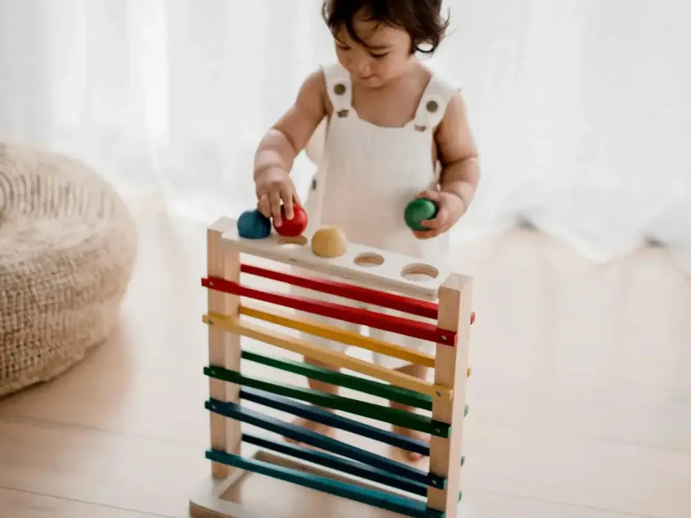 Wooden toy with colorful horizontal bars and balls for children to manipulate.