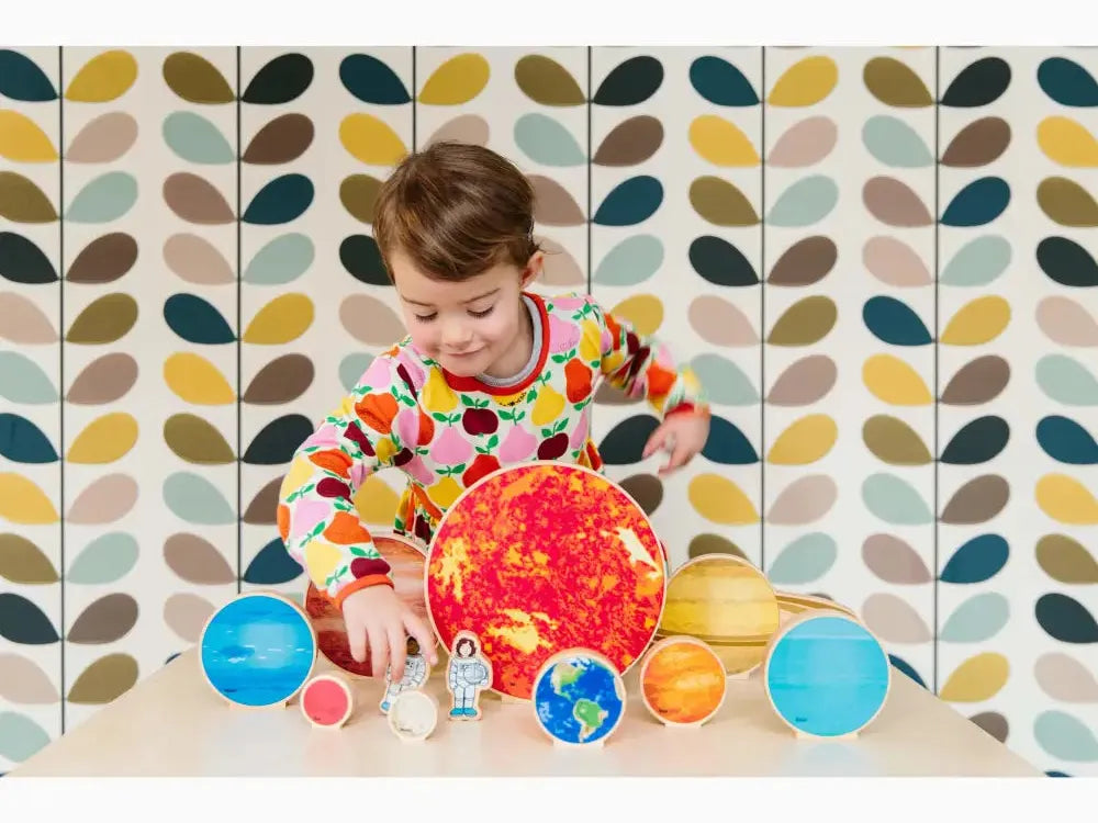 Child playing with a colorful model of the solar system.
