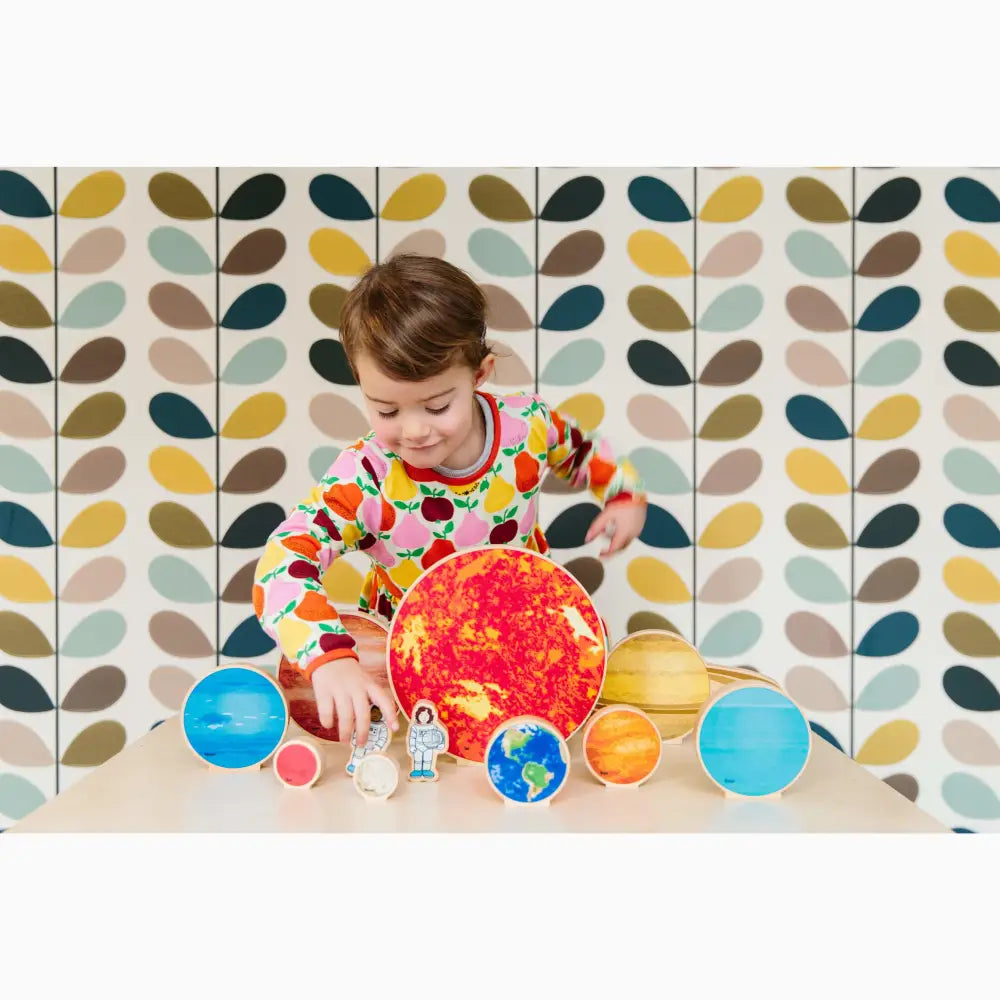 Child playing with a colorful model of the solar system.