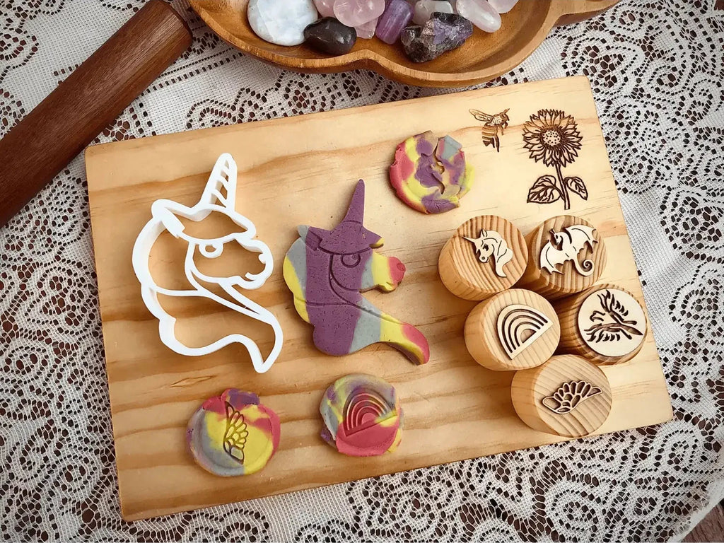 Wooden cutting board displaying various cookie cutters and stamped cookies with colorful designs.