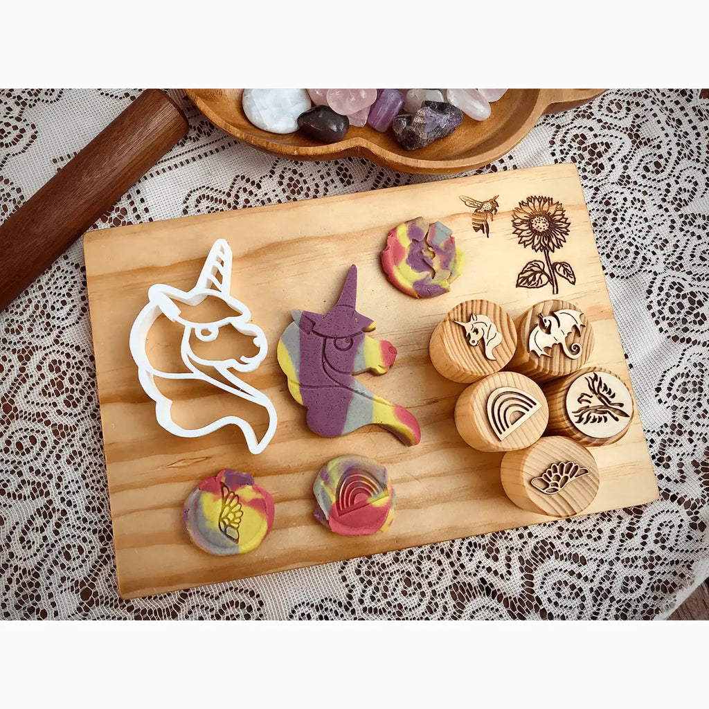 Wooden cutting board displaying various cookie cutters and stamped cookies with colorful designs.