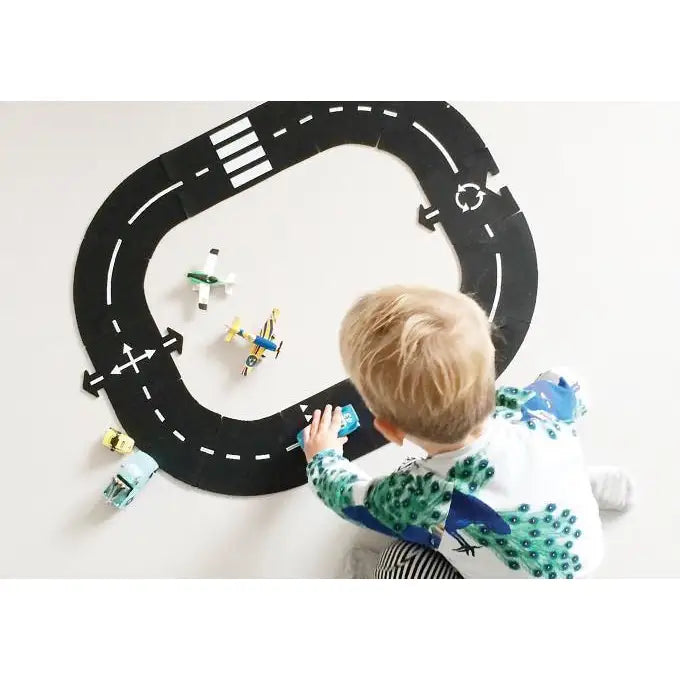 Flexible toy race track with white dashed lines on a black surface.