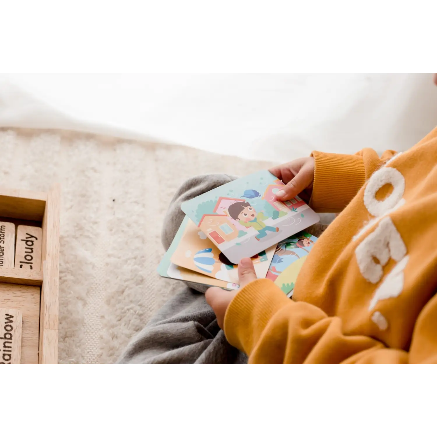 Hands holding colorful illustrated cards or flashcards.