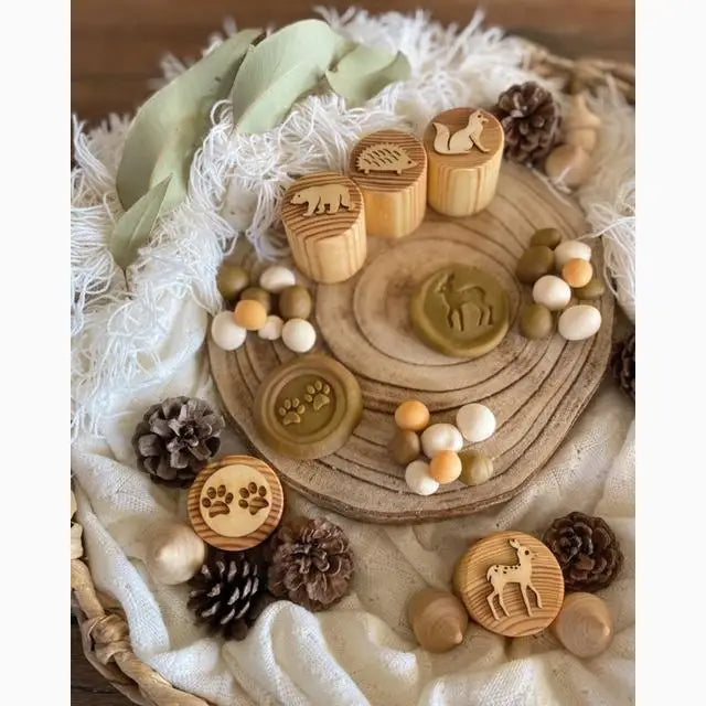 Wooden circular board with assorted natural objects and small wooden stamps arranged on top.