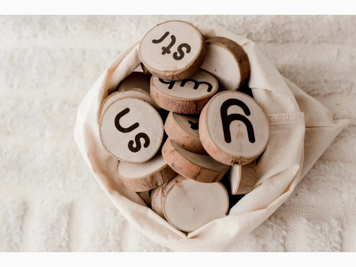 Wooden discs with letters and symbols carved on them, gathered in a fabric pouch.