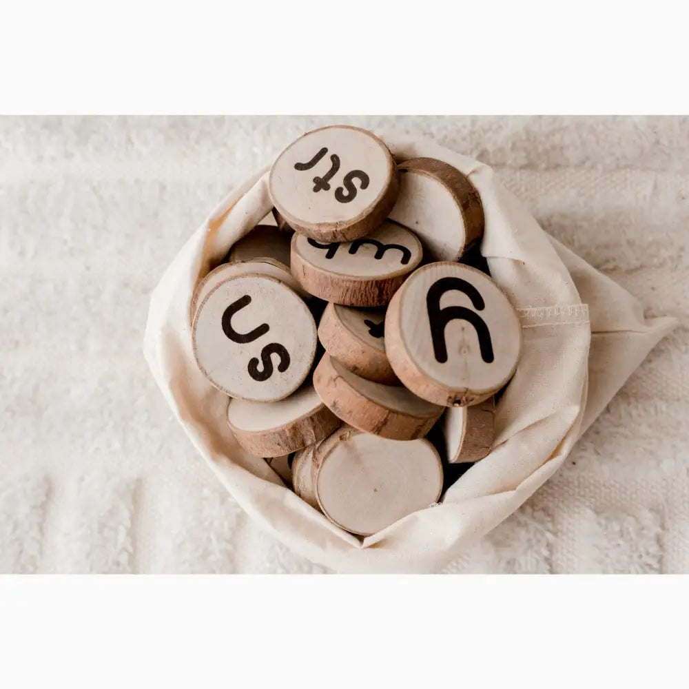 Wooden discs with letters and symbols carved on them, gathered in a fabric pouch.