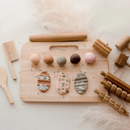 Wooden board with colorful clay shapes and various wooden tools.