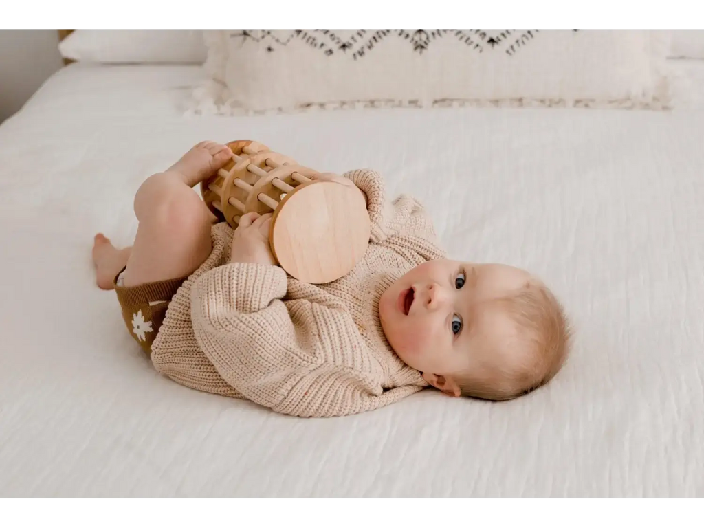 Baby lying on its back wearing a beige knit sweater.