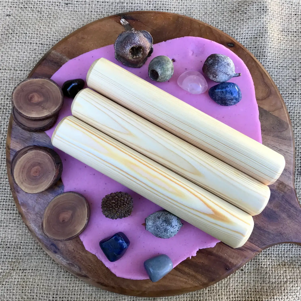 Wooden board with purple resin inlay holding crystals, stones, and palo santo sticks.