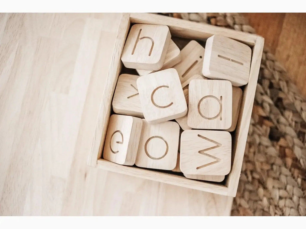 Wooden blocks with engraved letters in a box.