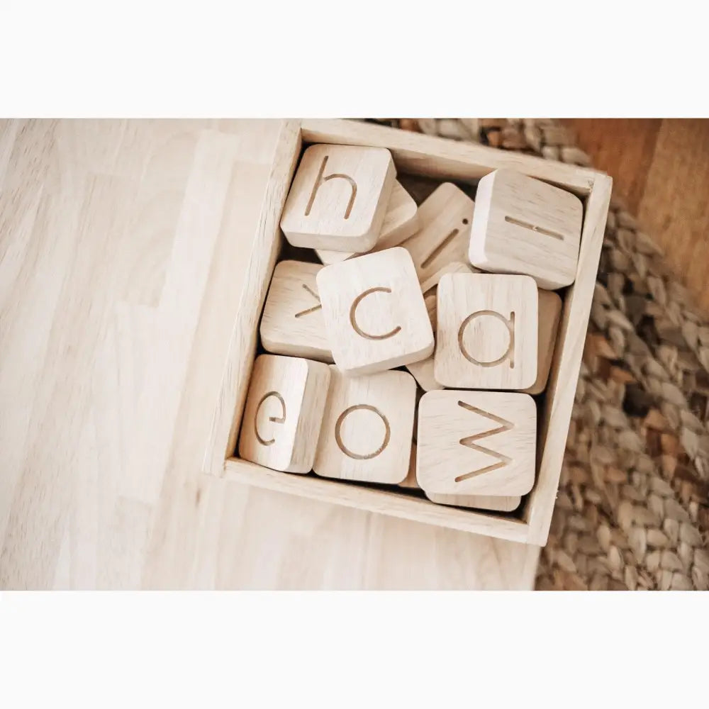 Wooden blocks with engraved letters in a box.